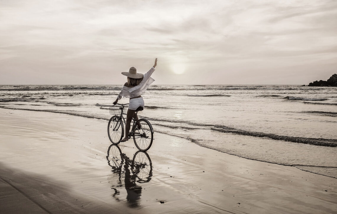 A woman riding a bike on the beach